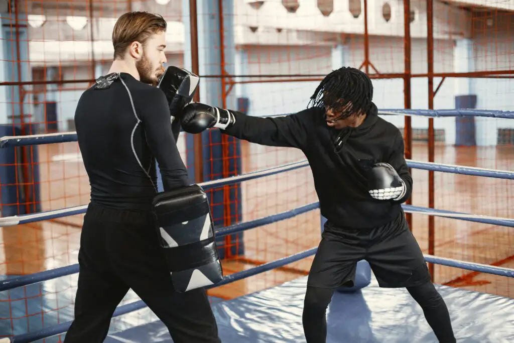 Boxing student hitting pads with the coach